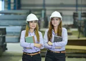 Two female engineers wearing safety helmets in an industrial workplace